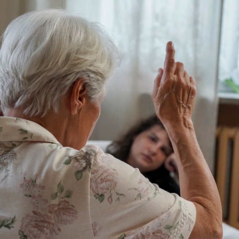 obrazek dekoracyjny - przedstawia starszą kobietę z uniesiona dłonią i palcem wskazującym